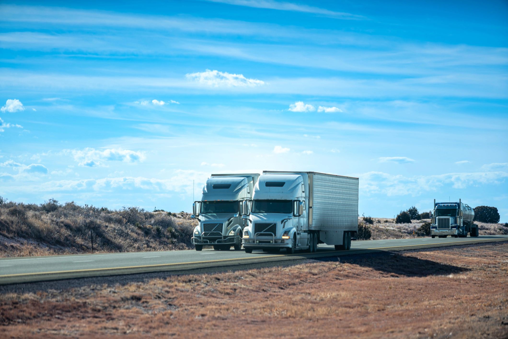Two semi-trucks with trailers parked side by side